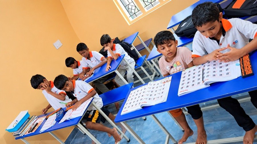 Children in Mastermind Abacus uniforms practising abacus and mental maths worksheets in a classroom
