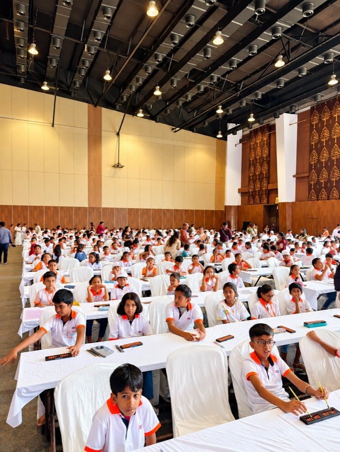 Hundreds of Mastermind Abacus students seated with their abacus tools in a large hall for an abacus competition