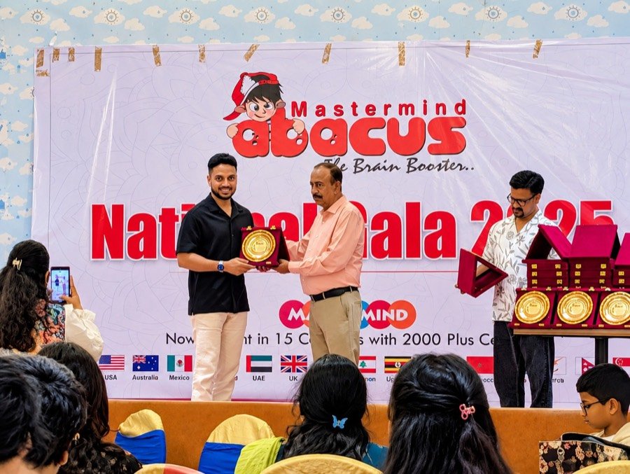 Mastermind Abacus Odisha receiving a gold plaque on stage at the Mastermind National Gala 2025